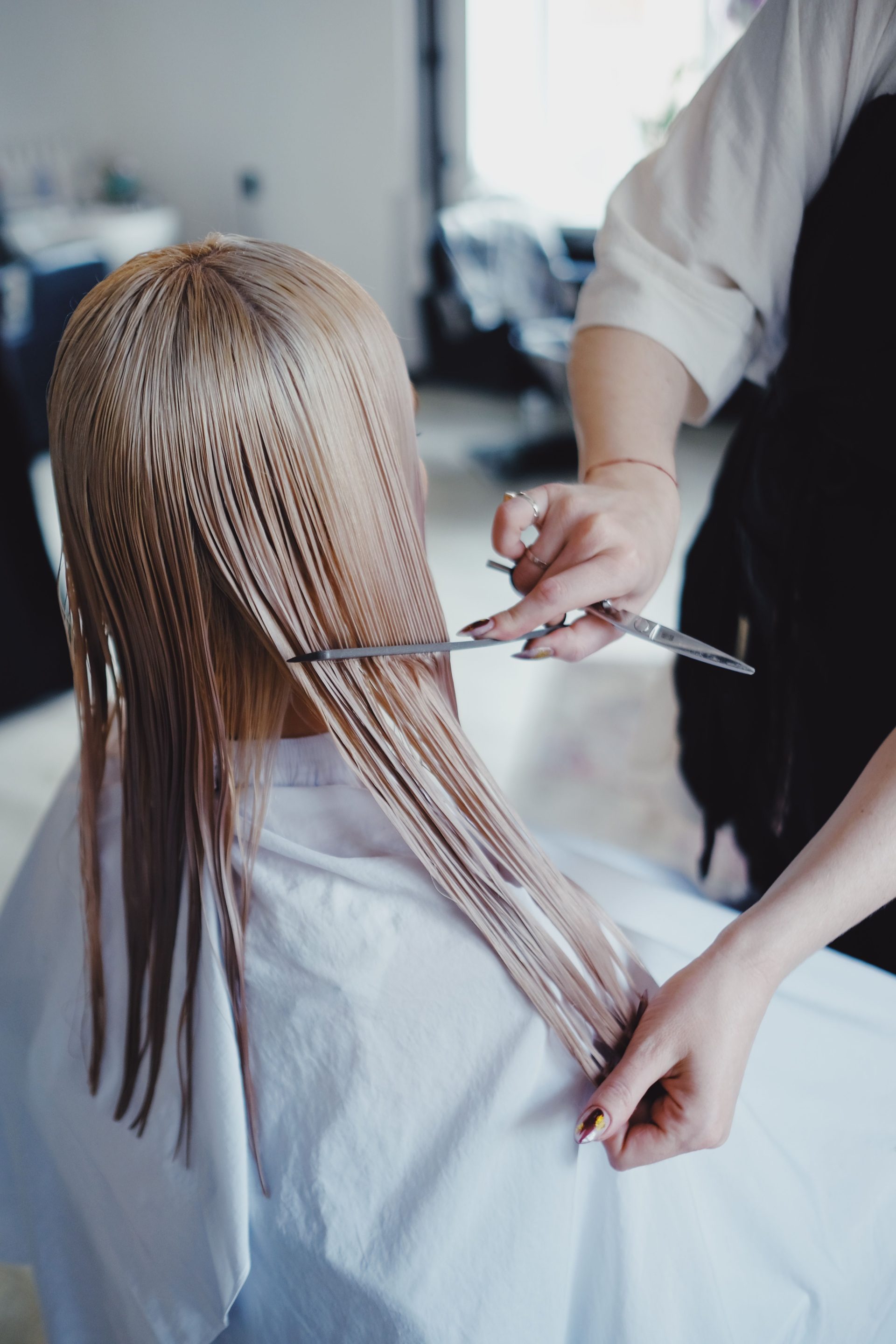 Blond woman receiving a professional haircut in a modern salon, showcasing precise scissor work.